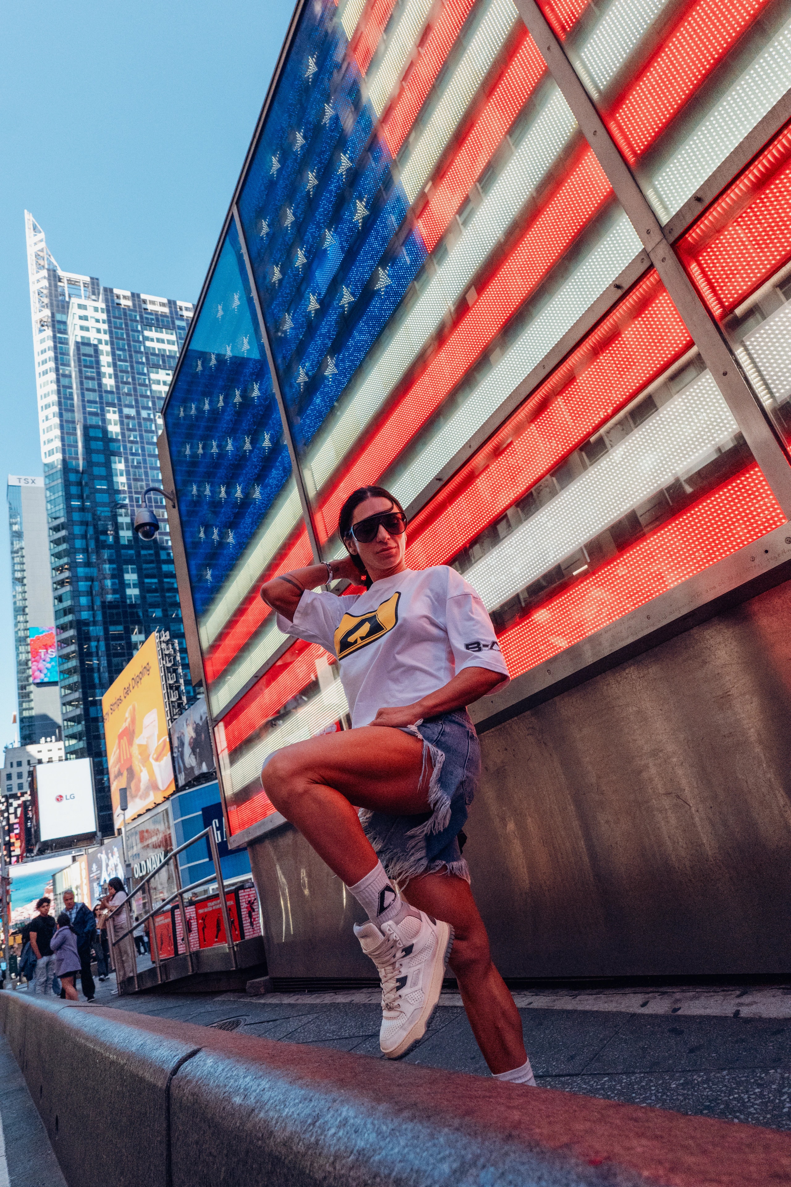 A person in sunglasses poses beside an American flag LED facade.